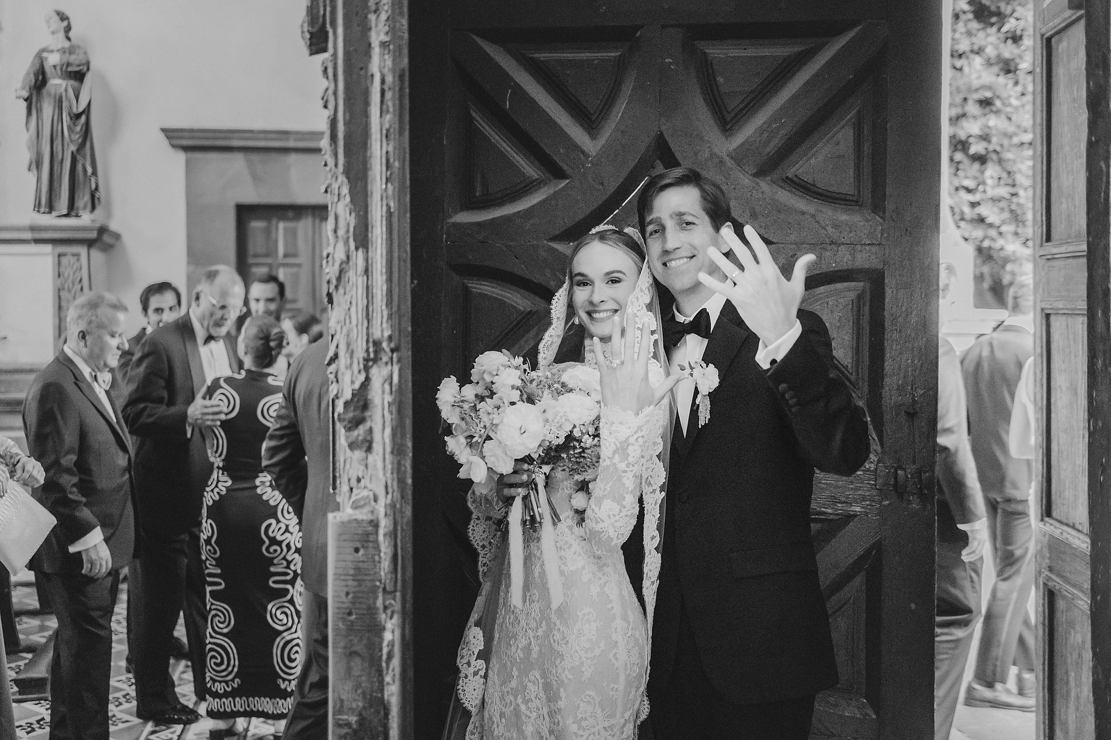 Newlyweds showing wedding rings at church door in San Miguel de Allende