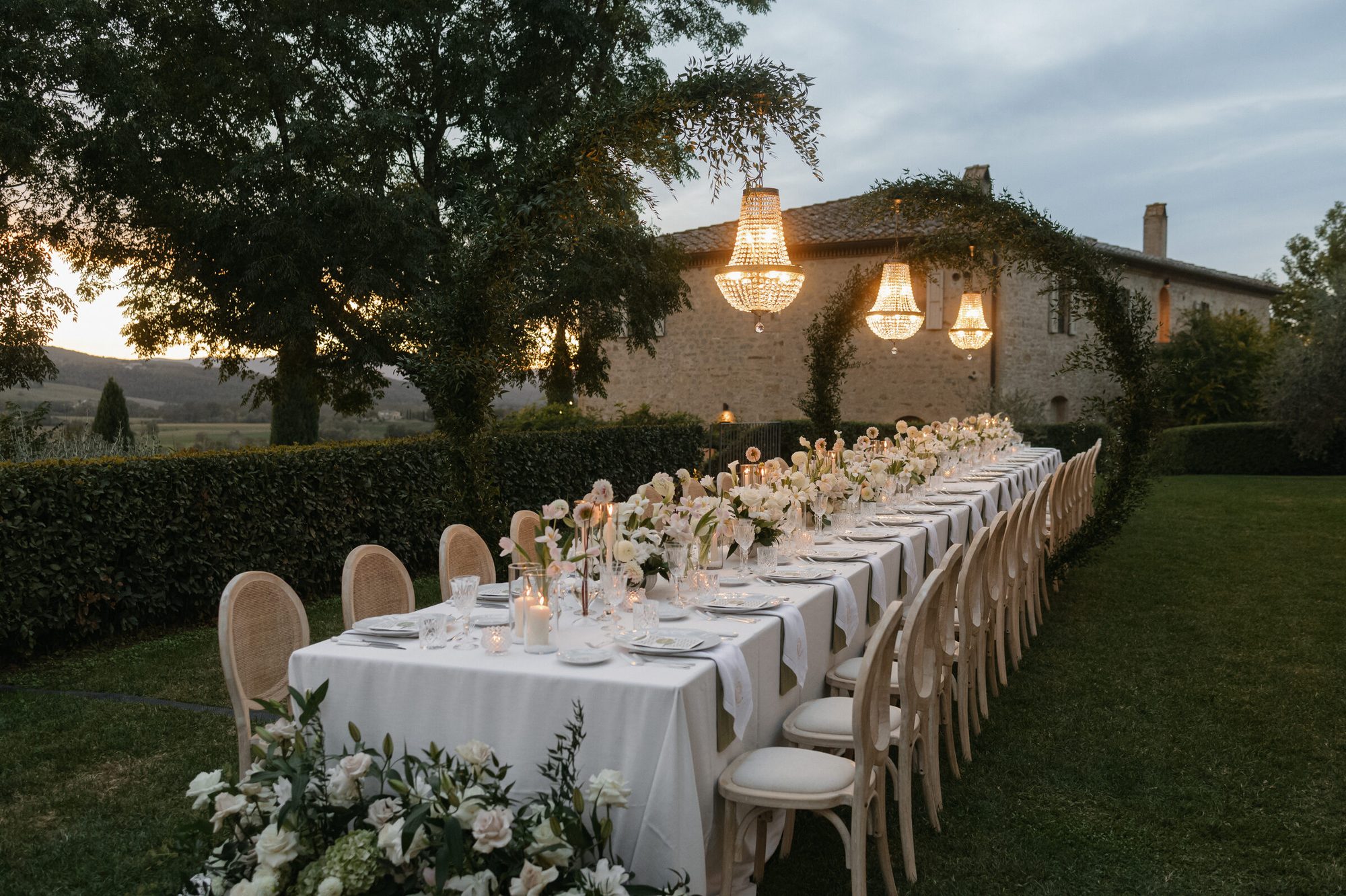 Al fresco dinner at twilight with string lights at Ombroneta Villa Tuscany destination wedding