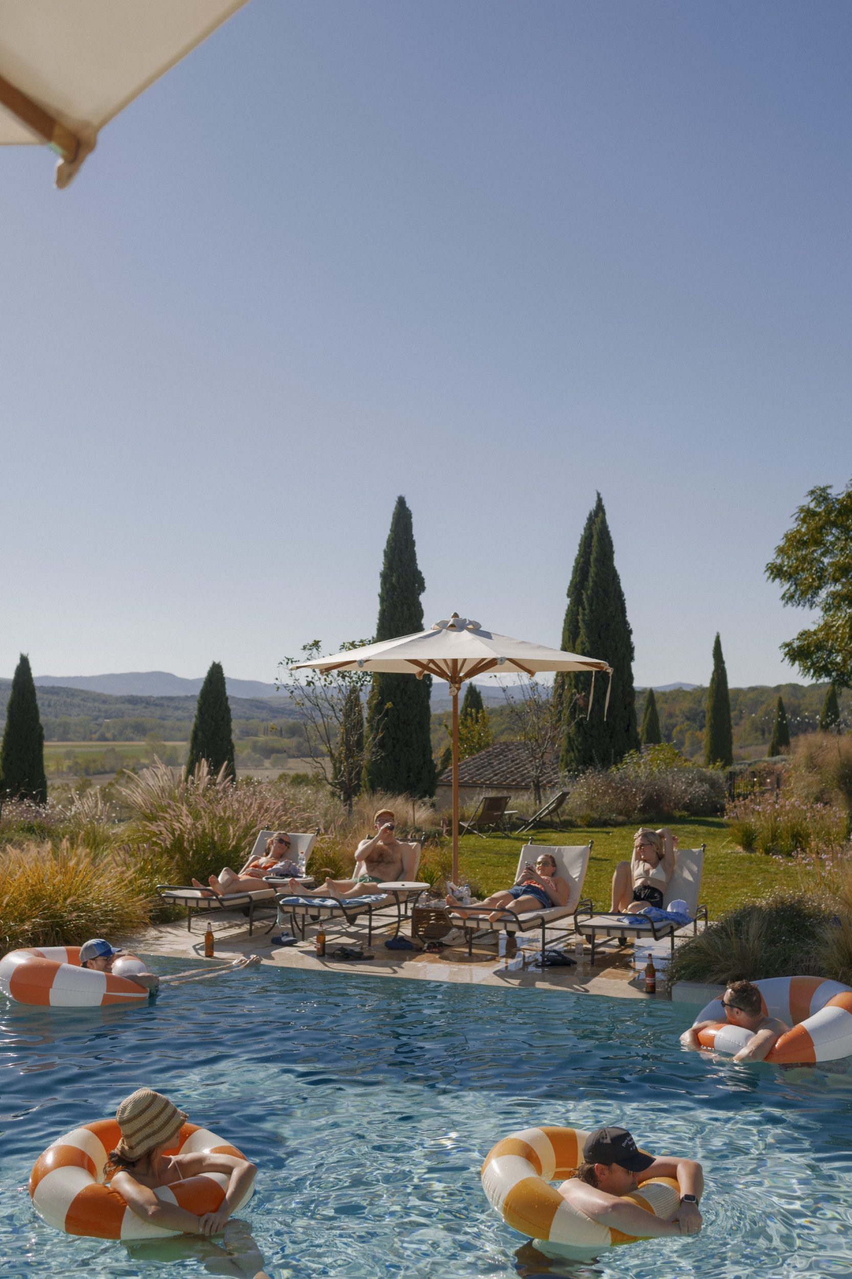 Wedding party splashing in villa pool with Tuscan hills in background