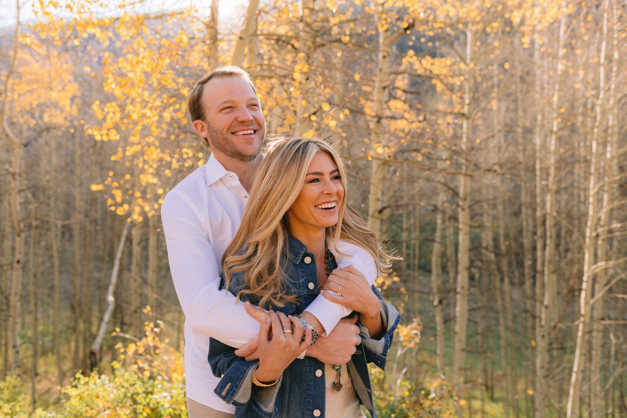 Couple embracing among golden aspens during fall engagement session Aspen Colorado