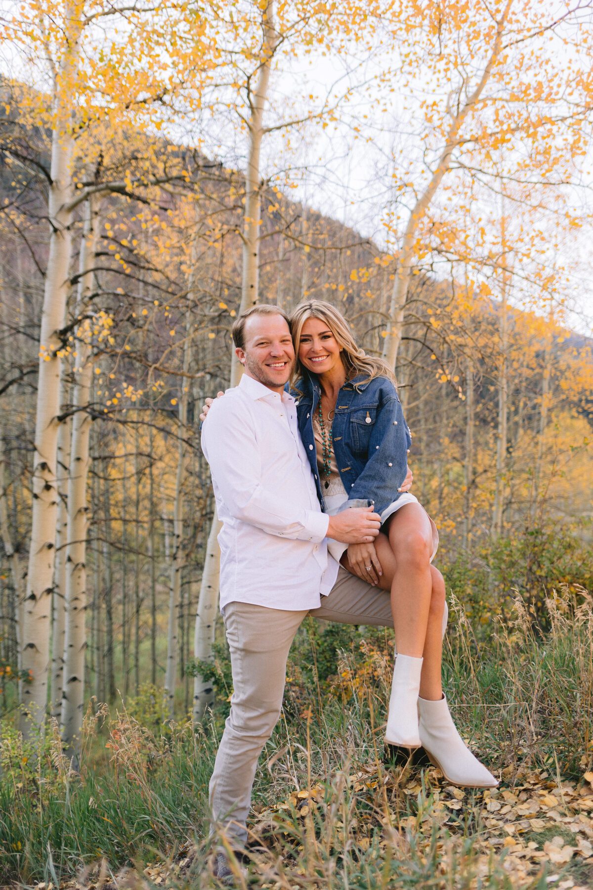Laughing engagement portrait in golden aspen grove Elk Mountains Colorado