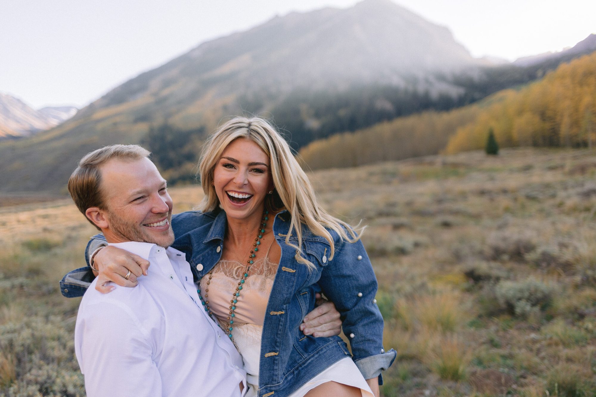 Couple on mountain road with fall color backdrop Aspen engagement photographer