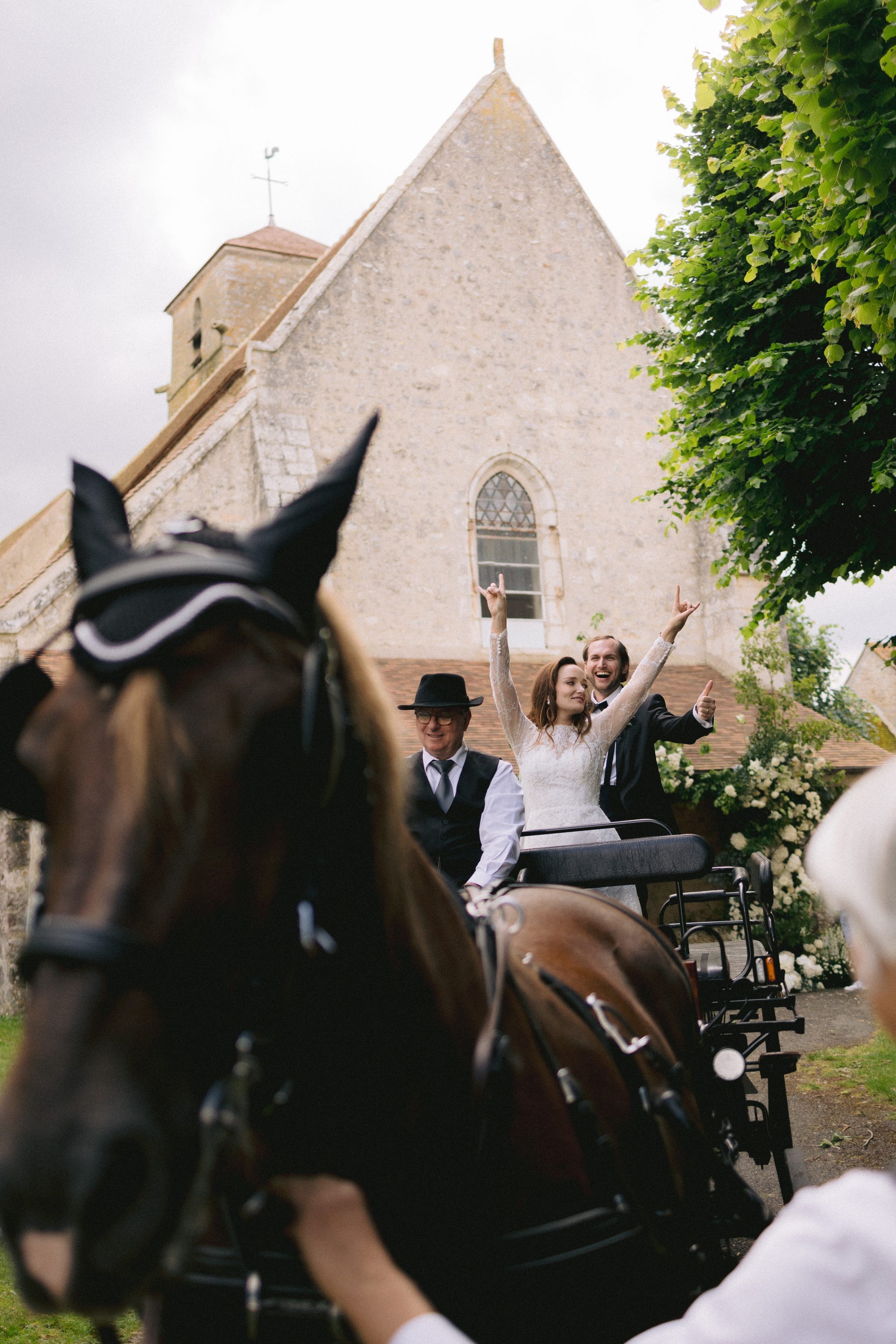 Couple departing in horse-drawn carriage from French chateau wedding