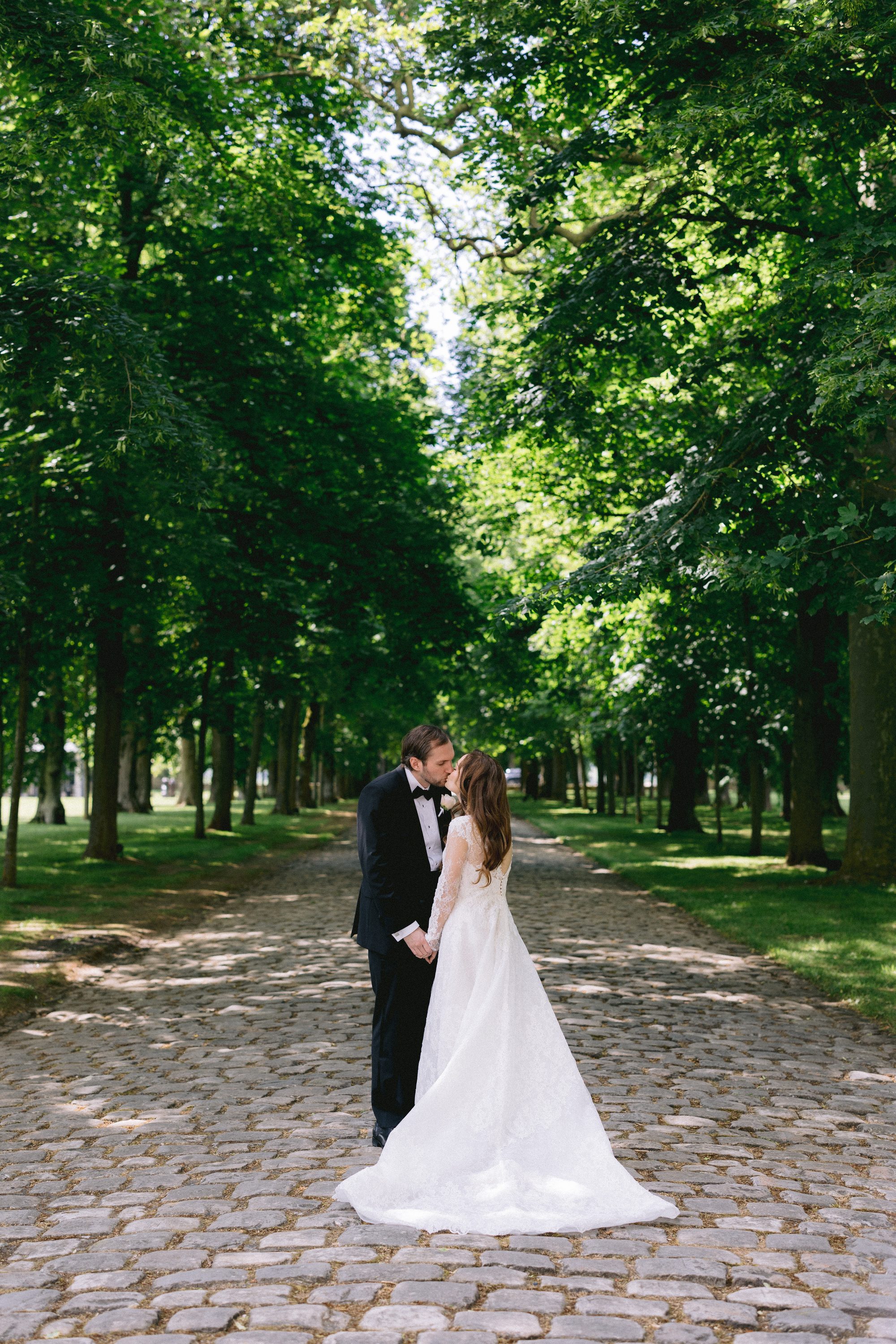 Couple kissing under tree-lined allee at Chateau de Farcheville France