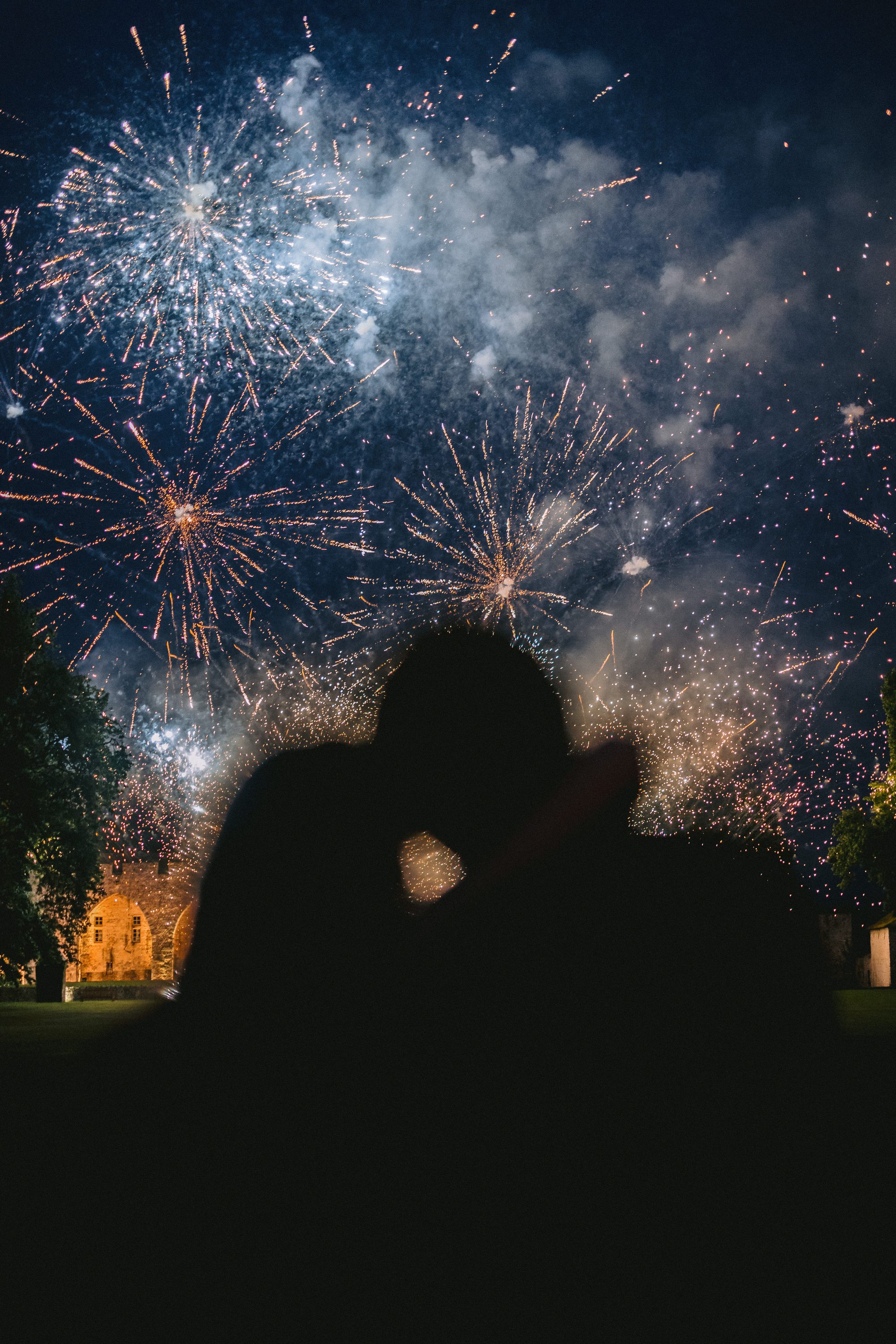 Couple kissing with fireworks at Chateau de Farcheville France destination wedding Marco Wang